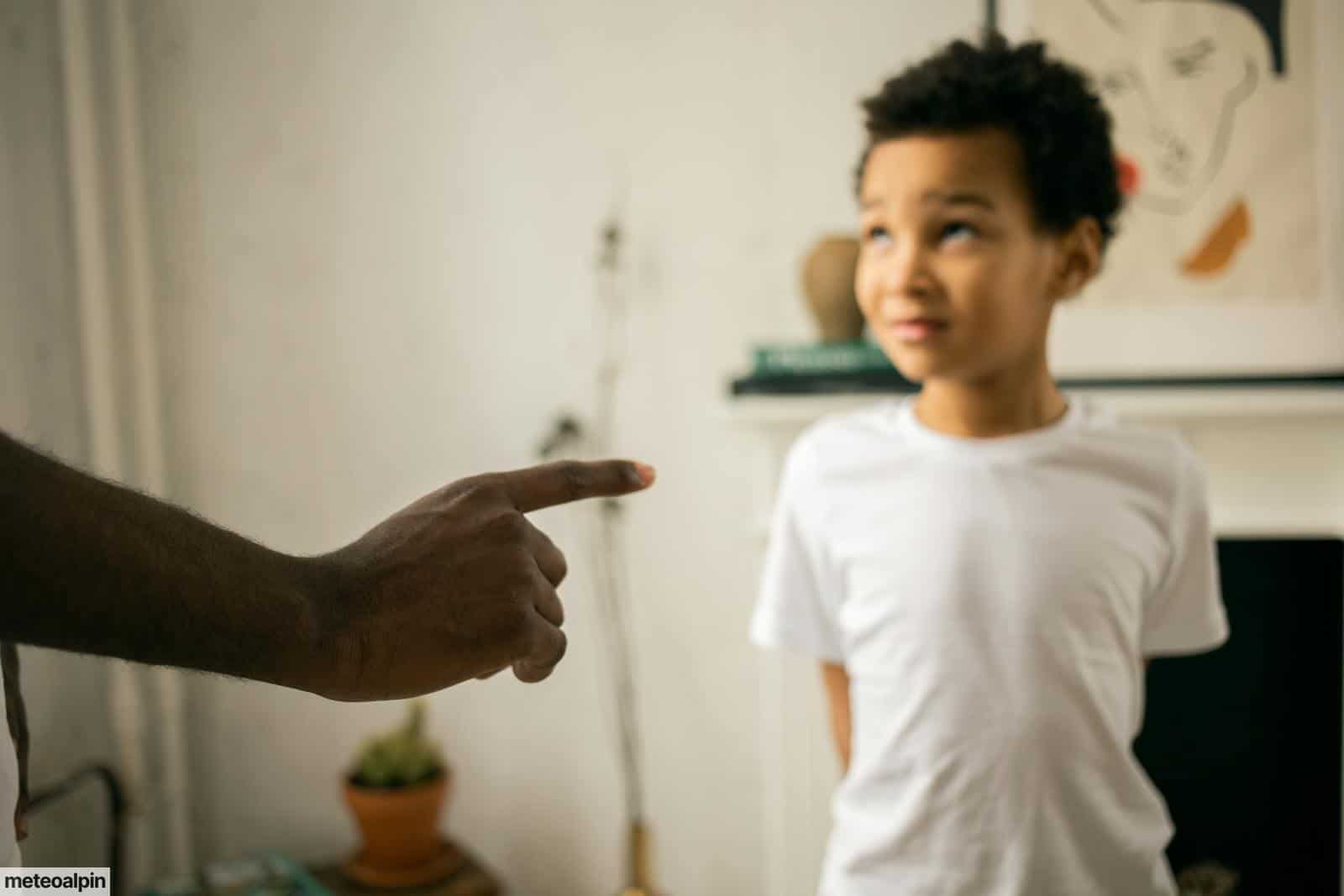 Upset little ethic boy looking at faceless father during argument